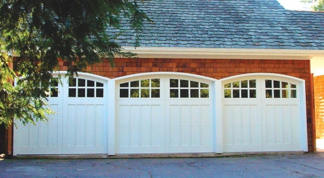 Garage with cedar shingles and three carriage house style garage doors painted in white