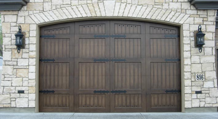 Garage with light color stone siding and dark carriage house garage door
