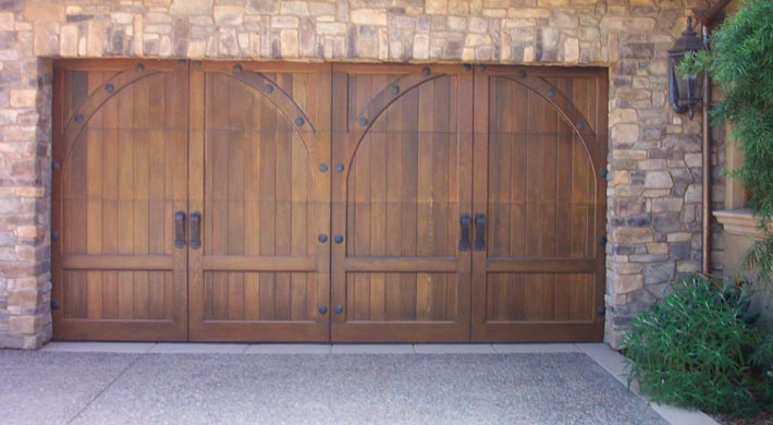 Wood carriage house doors with large handles on structure with stone siding