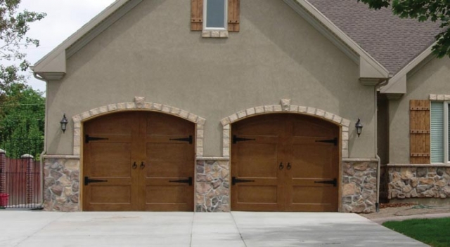 House with stucco and stone siding, two wood carriage house garage doors