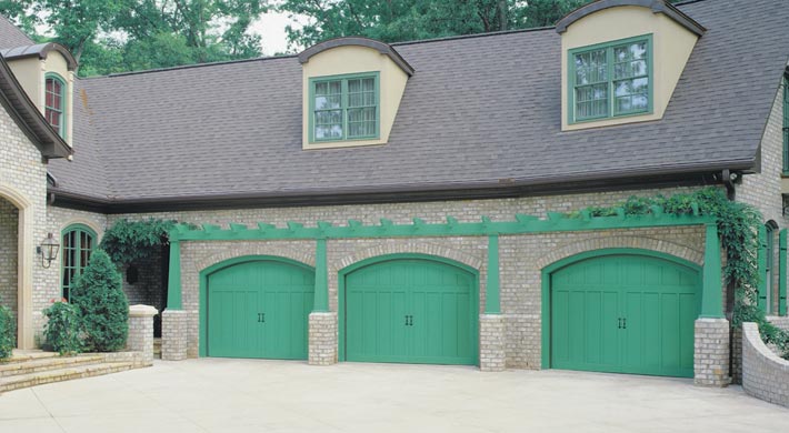 three car garage with three arch top amarr by design garage doors painted in green