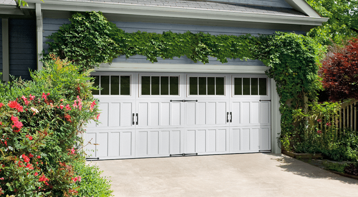 Close up of garage door on home with two car-garage, house has blue siding and lots of foliage