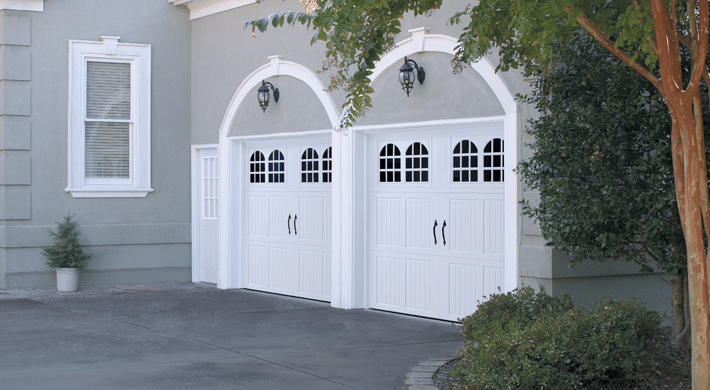 Photo of two car-carage with two white carriage house style garage doors with four windows on each door