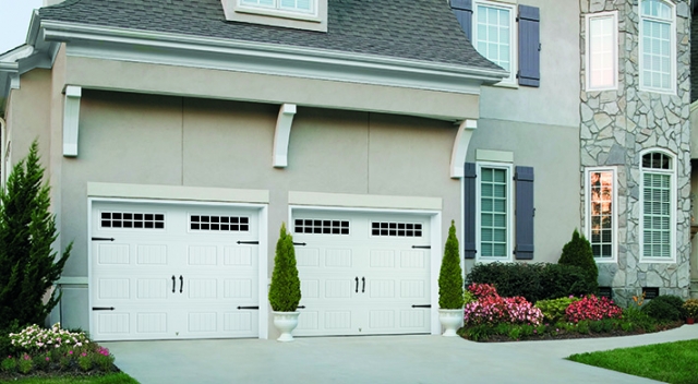 Two story house with stucco siding and two white garage doors