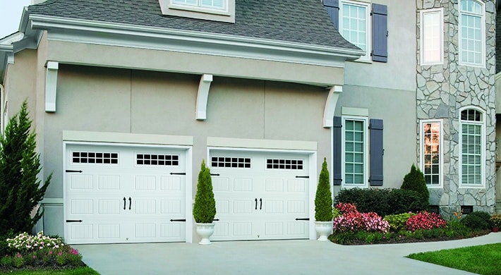 attached two car garage with two white garage doors on two story house