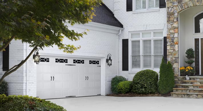Two story house with painted white brick siding and white garage door with black hardware