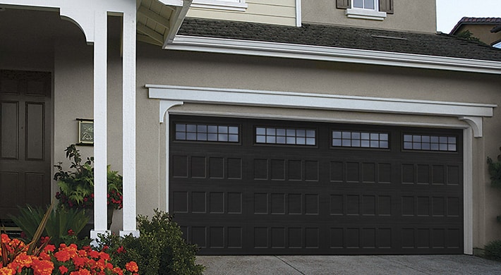 Black garage door on two story house with stucco siding and white trim