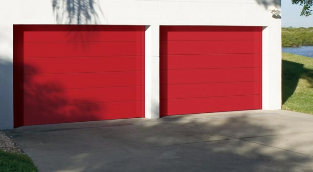Two flush bright red garage doors on garage with white stucco siding