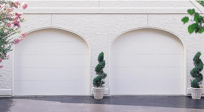 Two flush white garage doors on garage with arch garage openings