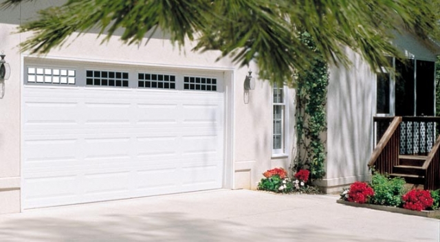 Attached garage with white garage door on house with stucco siding