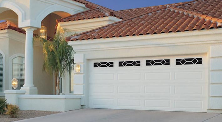 Spanish style house with stucco siding, tile roofing, and white garage door