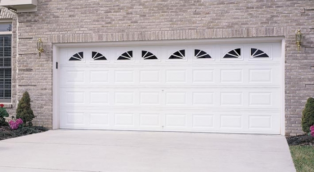 White garage door with windows on house with brick siding