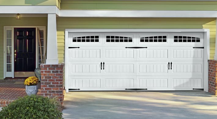 Yellow house with white trim and white carriage house style garage door