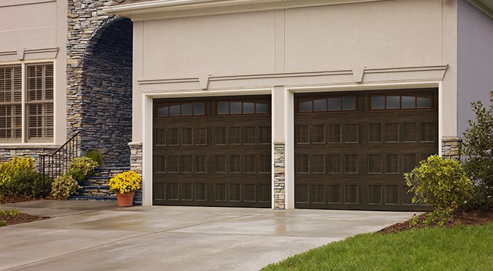 Two car garage with stucco siding and two dark garage doors