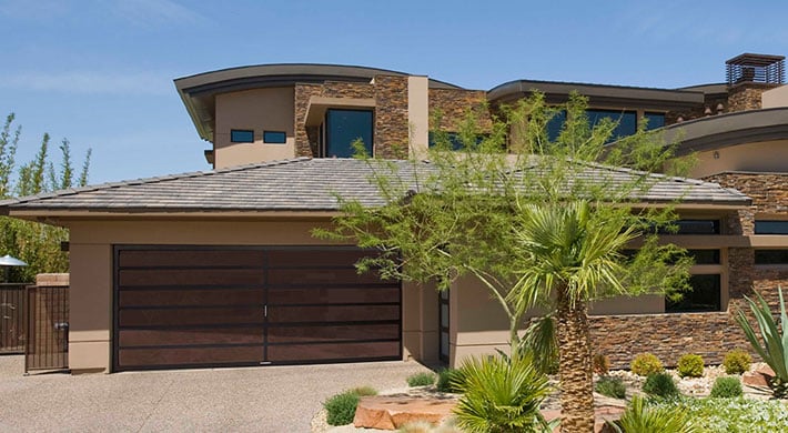 Two story luxury home with sand color stucco siding and specialty garage door