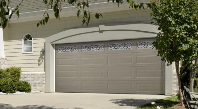 Long panel garage door with decorative windows on house with shingle siding