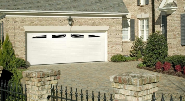 Long panel garage door with windows in the top panel on two-story house with brick siding