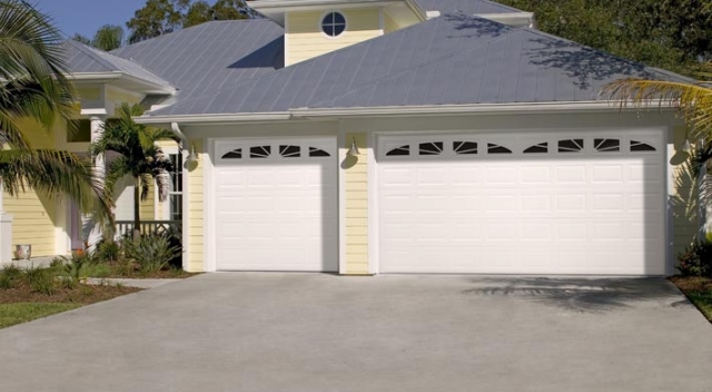 Three car garage with two garage doors on yellow suburban house