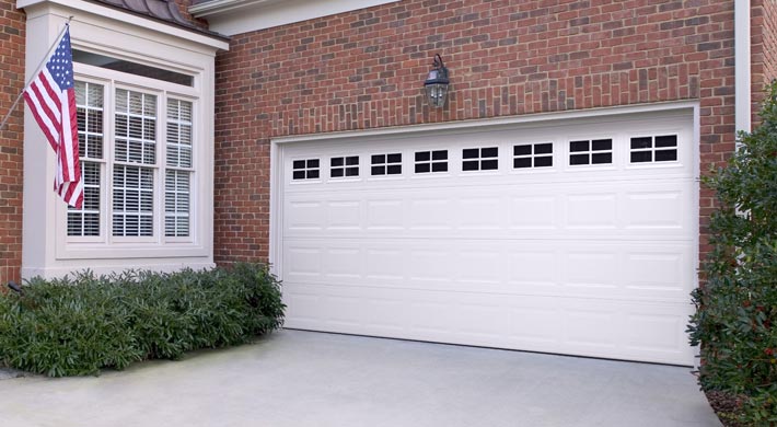 White garage door with windows in the top panel on attached garage with red brick siding