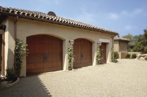 tan stucco house with arched garage doors