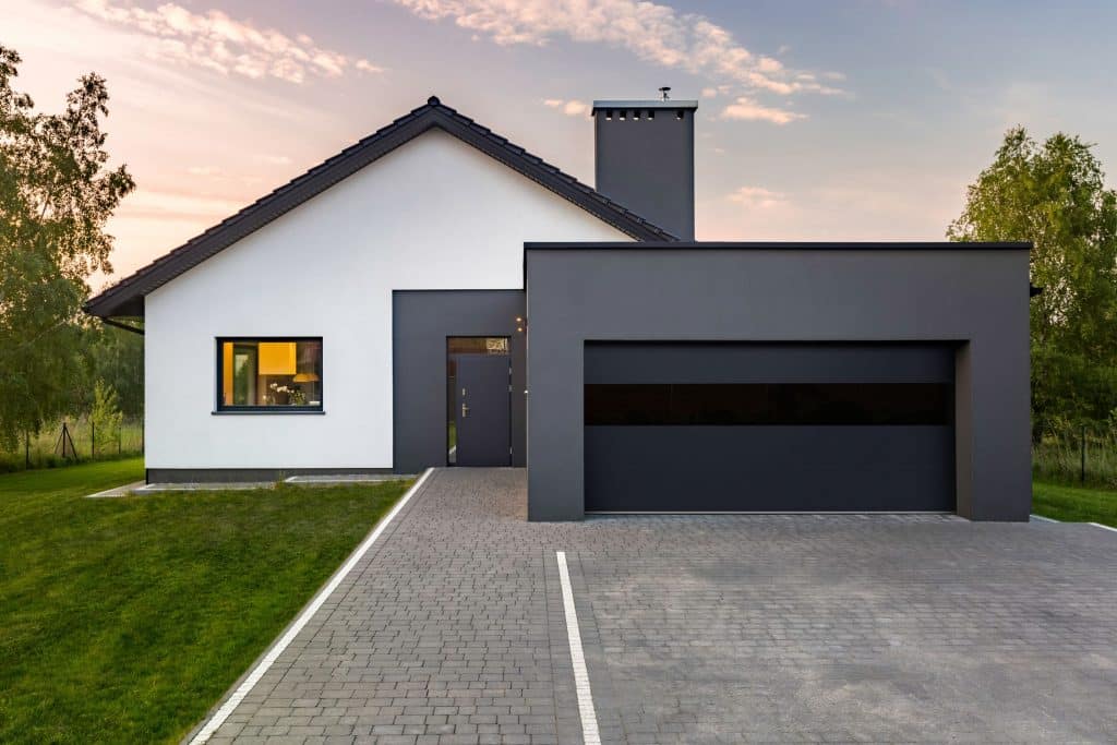 White and gray modern house with gray garage and dark CHI garage door with one black panel. Image for CHI vs Clopay Garage Doors comparison.