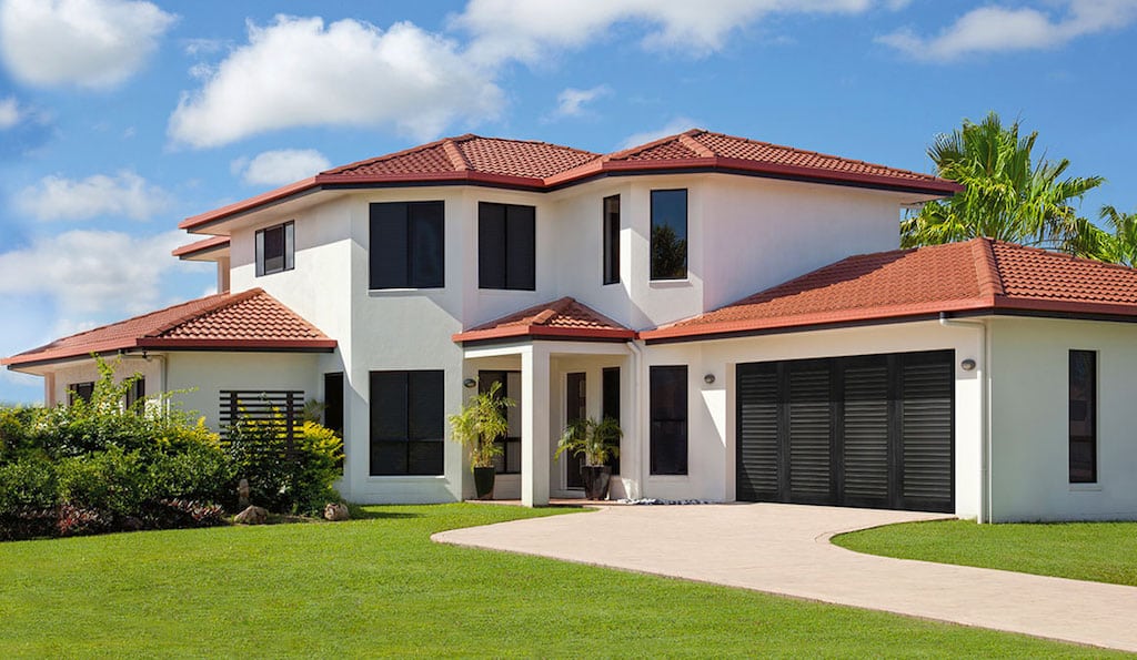 Modern white spanish style house with tile roof and black windows, entry door, and Clopay garage door. Image for CHI vs Clopay Garage Doors comparison.