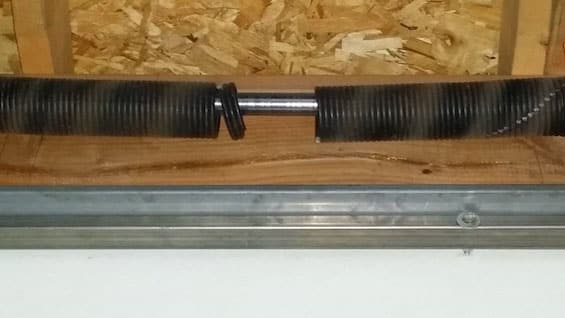 Garage door torsion spring with visible break in the center of the coil.