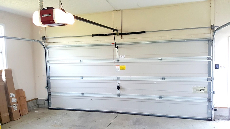 Photo of the interior of a garage with focus on the garage door with torsion springs. The image is for the post on best garage door spring system.