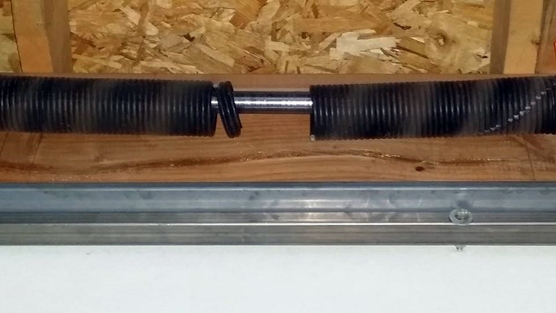 Close-up photo of a broken torsion spring for post on garage door spring repair cost.