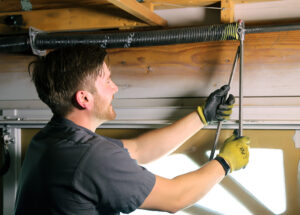 Photo of repairman tensioning a torsion spring for post on garage door spring repair cost.