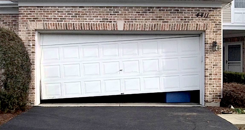 Photo of a crooked garage door for post on is it dangerous to replace garage door springs.