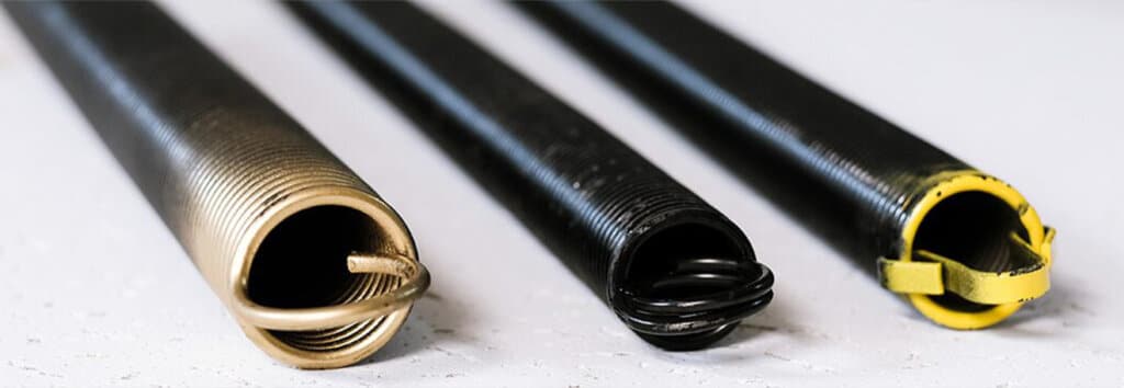 Photo of the ends of three extension springs. Color coated in gold, black, and yellow.