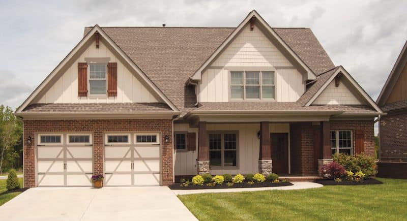 Photo of a two-story suburban house with two single-wide garage doors for post on garage door spring size chart.