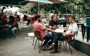 Photo of friends having a discussion while sitting at a restaurant patio.